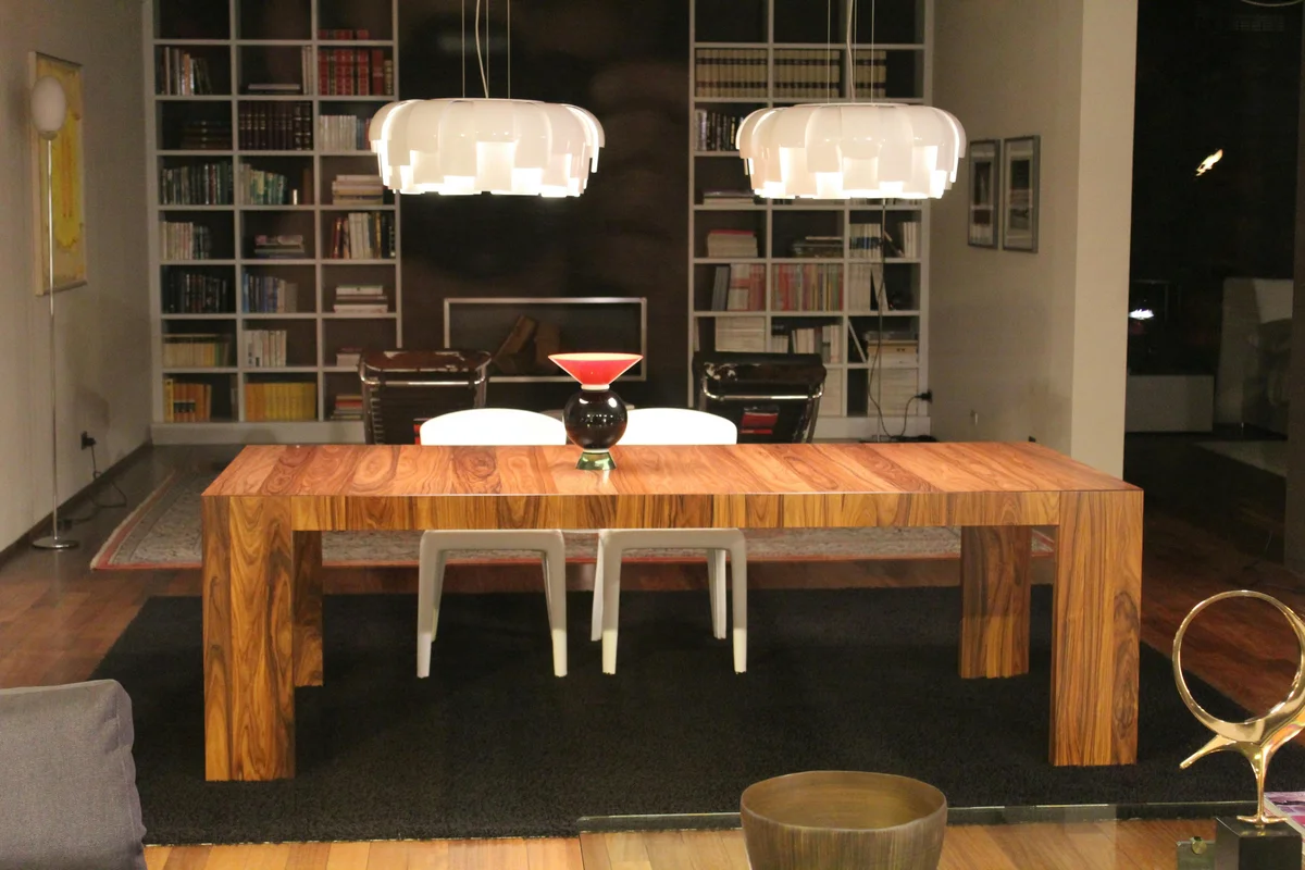 Wohnraum mit verschiedenen Möbel-Holzarten: Holztisch, Bücherregal und Holzdekor nebeneinander