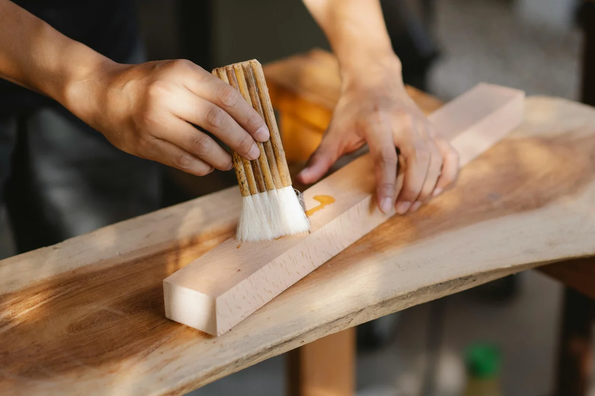Handwerker trägt Naturöl auf eine Massivholz-Tischplatte auf