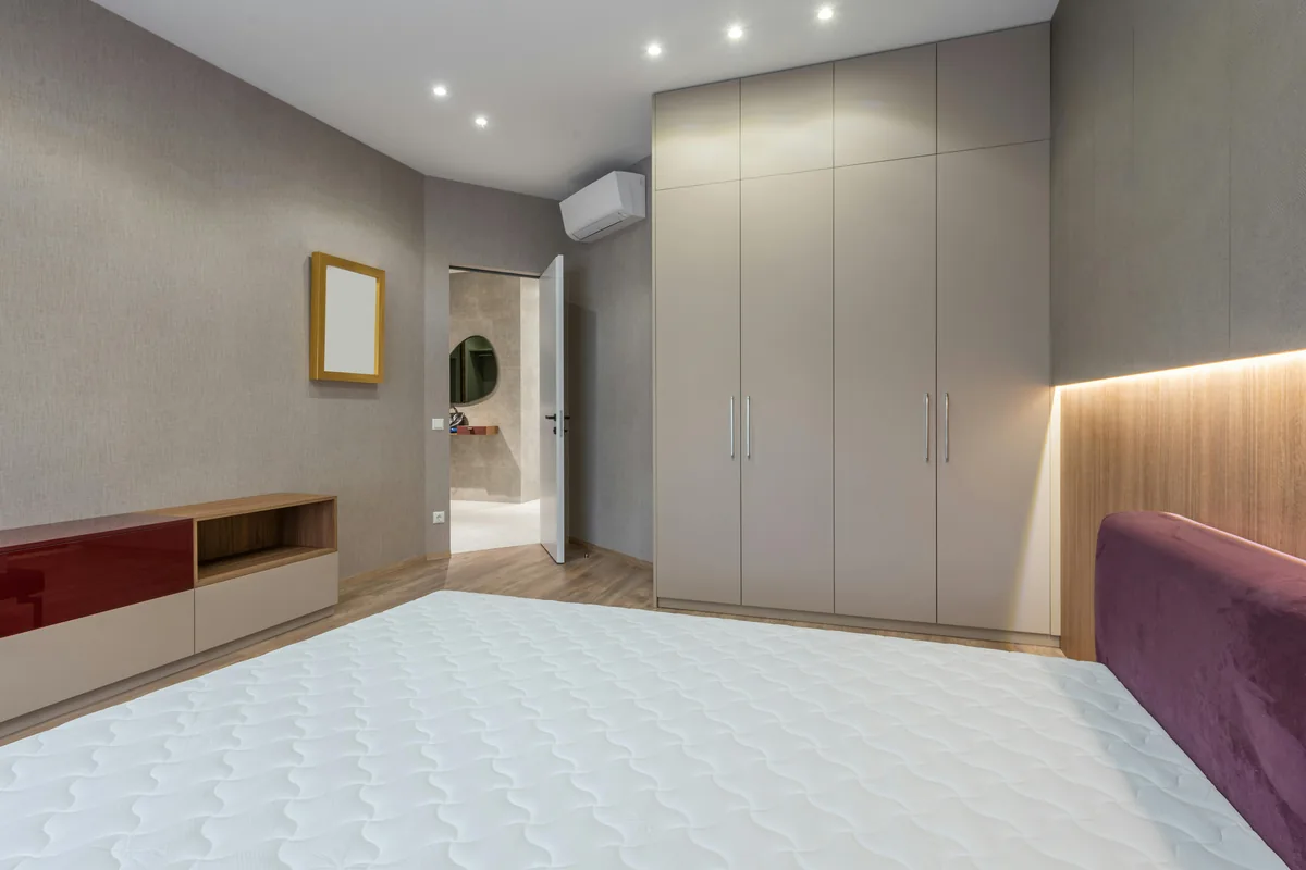 Bett mit sichtbarem Schubladenstauraum in einem kleinen Schlafzimmer, helles Interieur